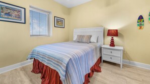 Ein Schlafzimmer mit einem Bett, einem Nachttisch, einem Deckenventilator und zwei gerahmten Bildern an der Wand.