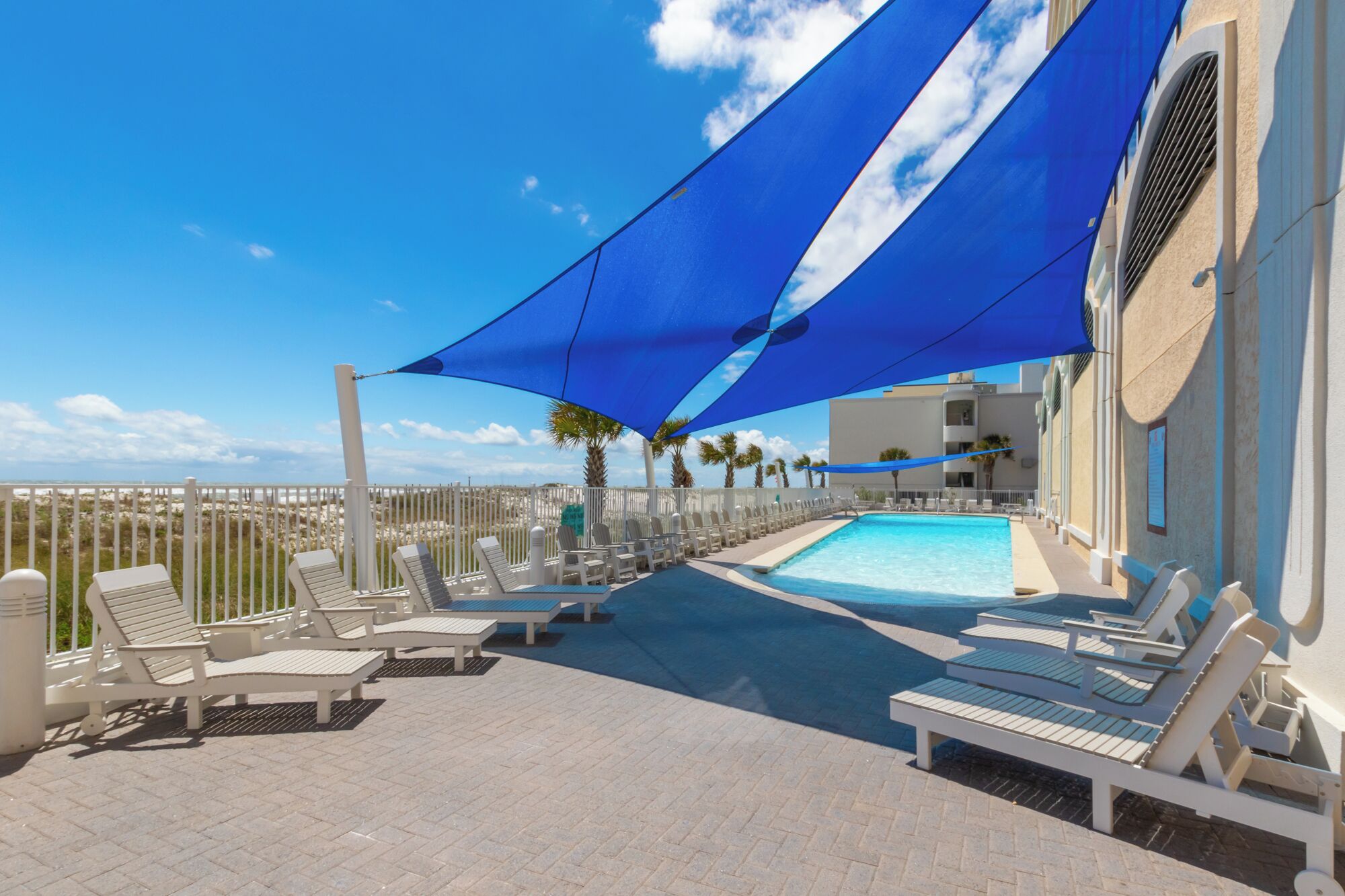 A poolside area with lounge chairs and a blue canopy.