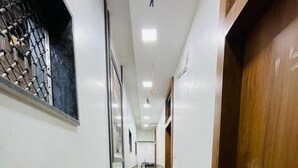 A hallway with a tiled wall, a wooden door, and a ceiling with recessed lighting. - HOTEL RADHA PALACE (Mumbai)