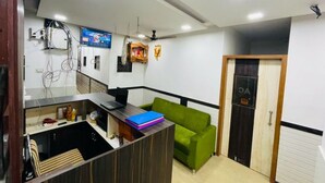 A modern kitchen with a wooden countertop, a green sofa, and a ceiling fan. - HOTEL RADHA PALACE (Mumbai)