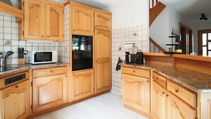 A kitchen with wooden cabinets, a microwave, an oven, and a toaster.