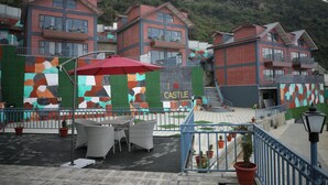 Un hôtel composé de plusieurs bâtiments aux façades en briques rouges, doté d’un espace extérieur avec des meubles en osier et d’une fresque colorée sur laquelle on peut lire : « J’♥ CASTLE ».
