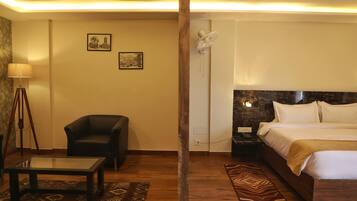 A hotel room with a bed, a chair, a table, and two wall-mounted artworks.
