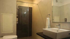 Une salle de bain comprenant des toilettes, une douche à parois de verre, un lavabo et un miroir.