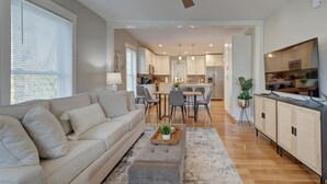 A modern living room with a sofa, coffee table, and a dining area with chairs and a table.