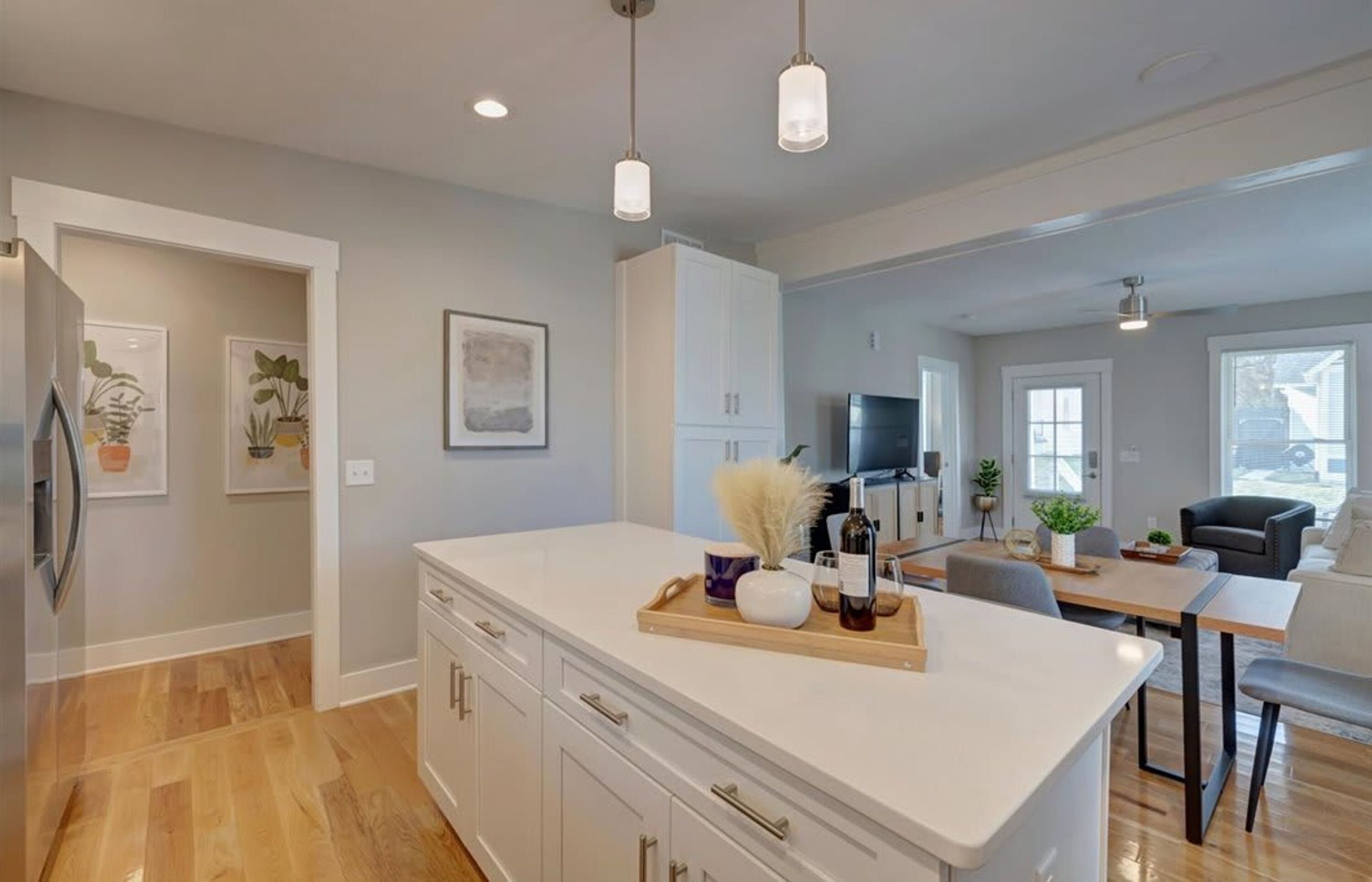 A modern kitchen with a central island, white cabinetry, and pendant lighting.