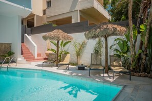 A swimming pool with lounge chairs and a staircase leading to an upper level.