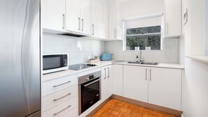 A compact kitchen with white cabinets, a microwave, a toaster, and a sink.