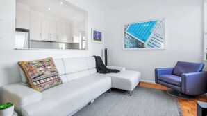 A modern living room with a white sofa, a blue armchair, and a gray rug.