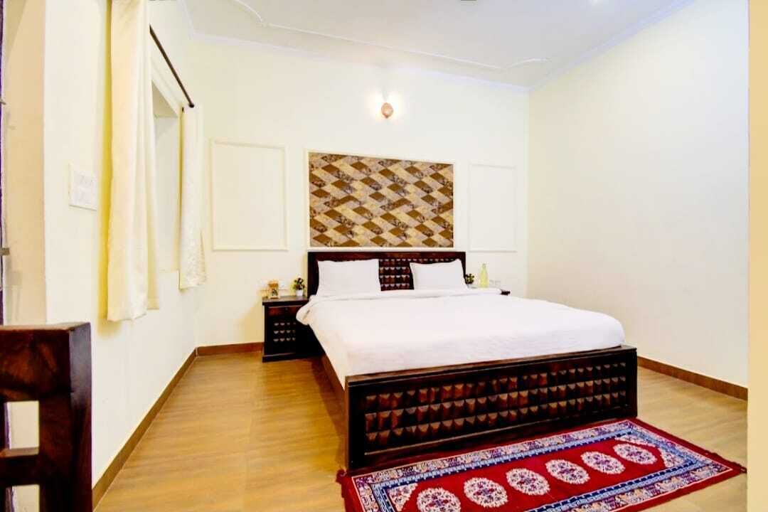 Un dormitorio con una cama de madera, un tapete de diseño rojo y azul, una lámpara de pared y un adorno mural estampado.