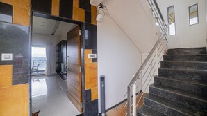 Ein modernes Interieur mit einer Treppe, Blick aufs Meer durch eine offene Tür und einer gefliesten Wand.