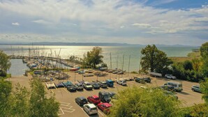 A marina with boats docked, a parking area with cars, and a view of the water and distant mountains. - Villa Azur on Lake Neuchâtel (La Grande Béroche)
