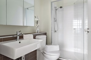 A modern bathroom with a white sink, toilet, and shower.