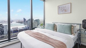 Ein modernes Hotelzimmer mit einem großen Bett, Blick auf die Stadt und einem gerahmten Bild an der Wand.
