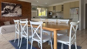 Une cuisine moderne avec des meubles blancs, une table à manger en bois et des chaises blanches.