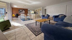 Un salon moderne avec un canapé bleu, une table basse en bois et un coin repas agrémenté d’un mur en briques et d’un tableau.