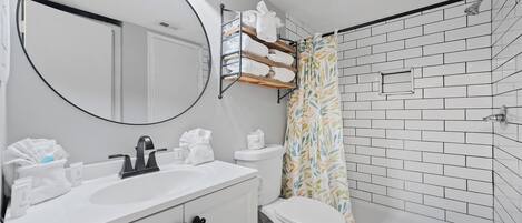 Un baño moderno con lavamanos blanco, inodoro y zona de ducha.