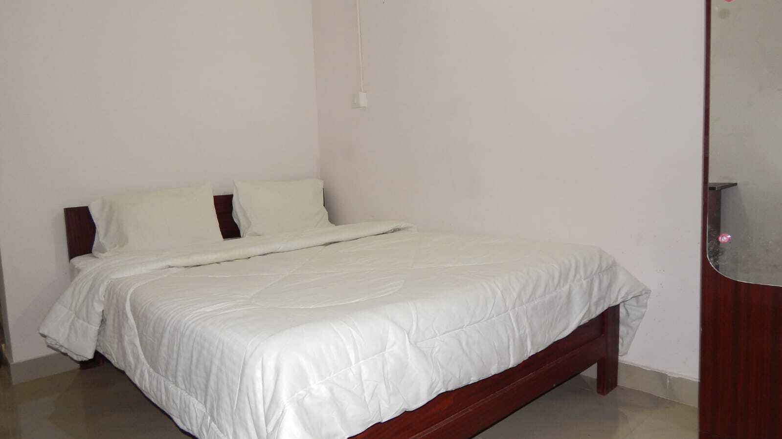 A single-bed room with a wooden headboard, white bedding, and a wooden nightstand.