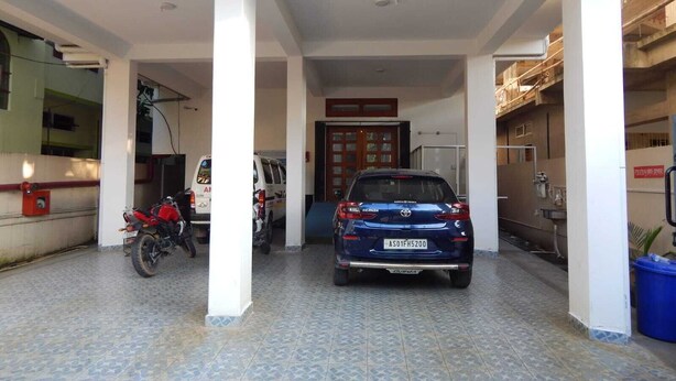 Área de estacionamento coberta com um carro azul e uma motocicleta estacionada.