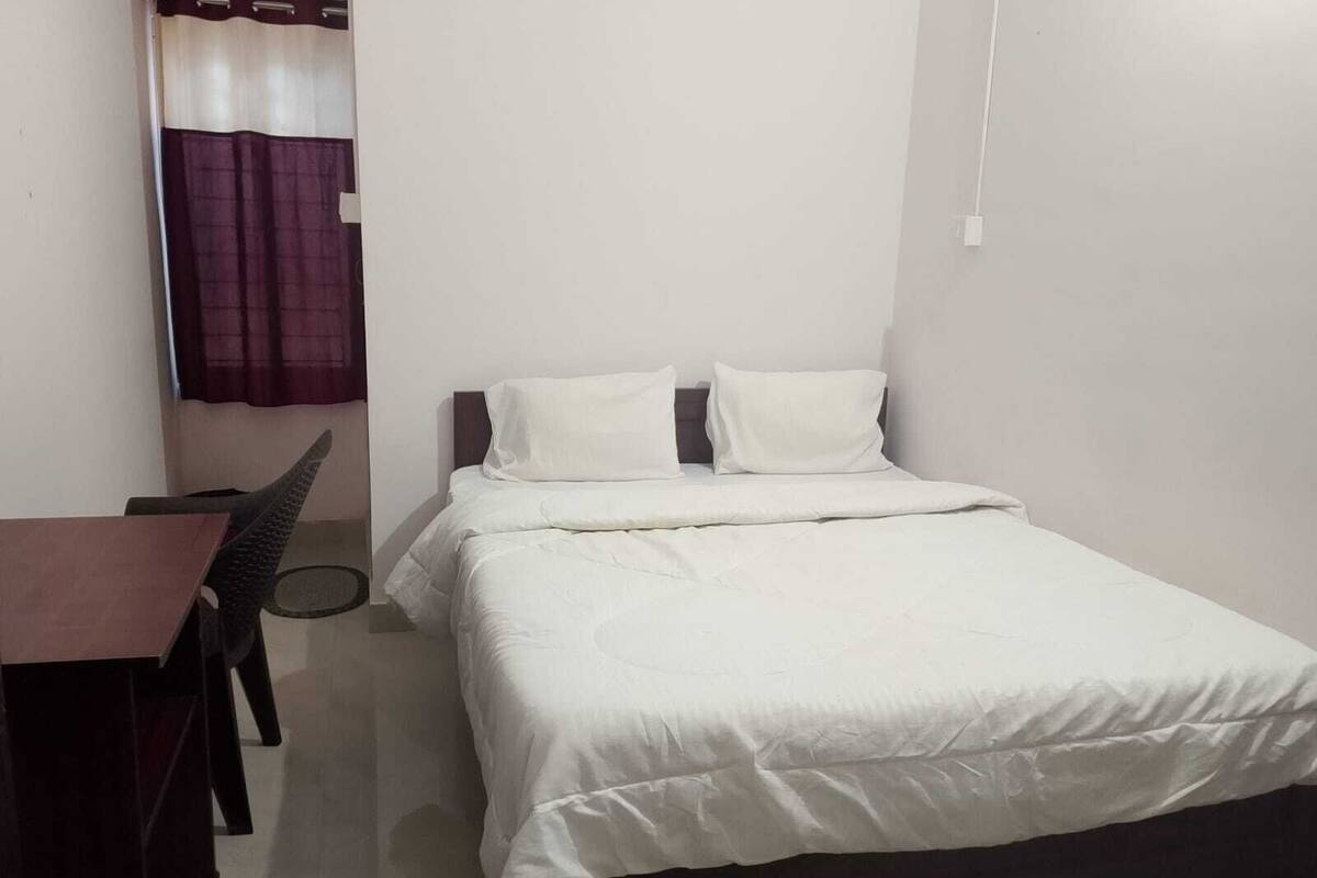 Una habitación pequeña y limpia con cama, escritorio y silla.