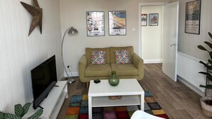 Una sala de estar con un sofá, una mesa de centro, un televisor y una decoración con forma de estrella en la pared.