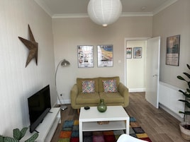 Una sala de estar con un sofá, una mesa de centro, un televisor y una decoración con forma de estrella en la pared.