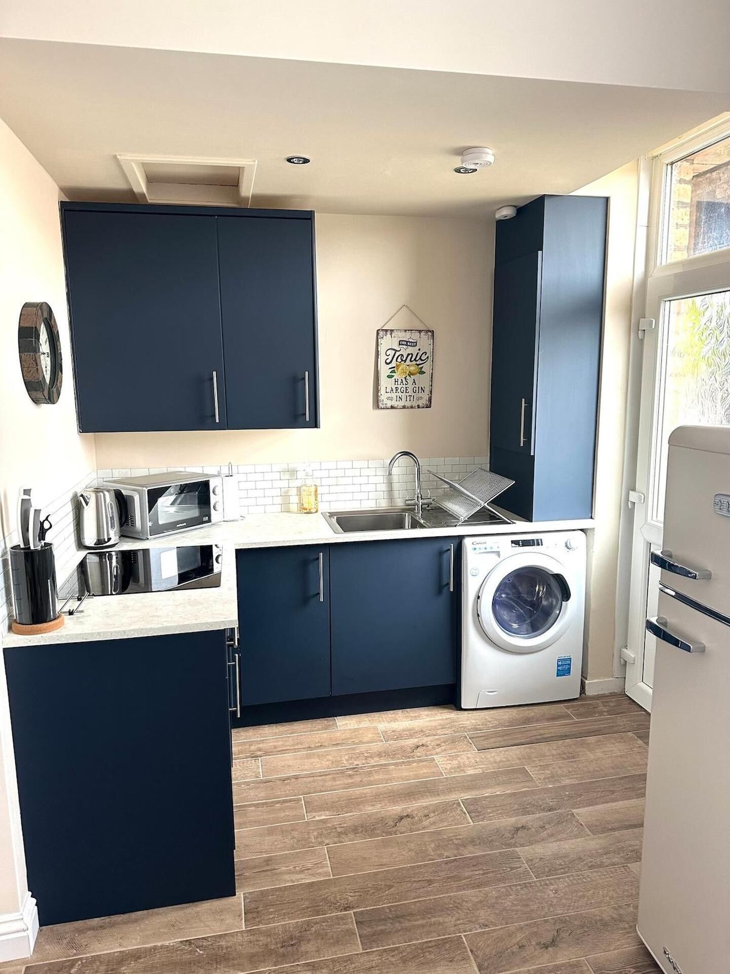 A compact kitchen with dark cabinets, a washing machine, and a microwave.