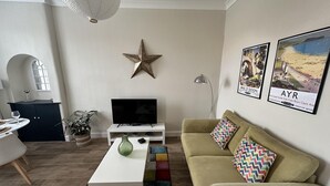 Una sala de estar con televisor, decoración con estrellas, un tapete colorido y dos cojines.