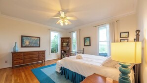 Un dormitorio con cama, cómoda, mesita de noche, lámpara y ventilador de techo.