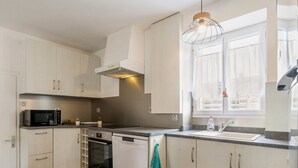 Una cucina moderna con mobili bianchi, un forno a microonde, un forno e un lavello.