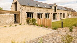 Un bâtiment en pierre avec un toit en pente, de nombreuses fenêtres et une allée gravillonnée.