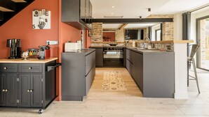 Une cuisine moderne dotée d’un îlot central, de meubles de couleur sombre et d’un escalier en bois.