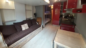 A compact living space with a sofa, kitchenette, and a small dining area.