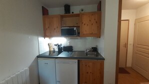 Une cuisine compacte avec des meubles en bois, un four à micro-ondes, un lave-vaisselle et un évier.