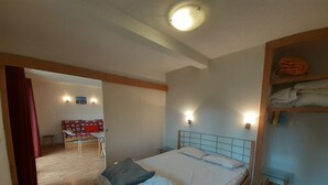 Un dormitorio con una cama, cabecera de madera, mesita de noche y armario.
