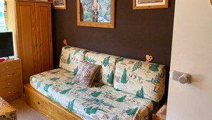 A cozy room with a wooden sofa, a wooden cabinet, and a framed painting on the wall.