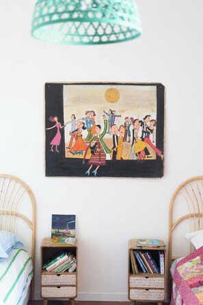 Cozy retreat with a wall-mounted art piece, woven rattan chair, and a comfortable bed.