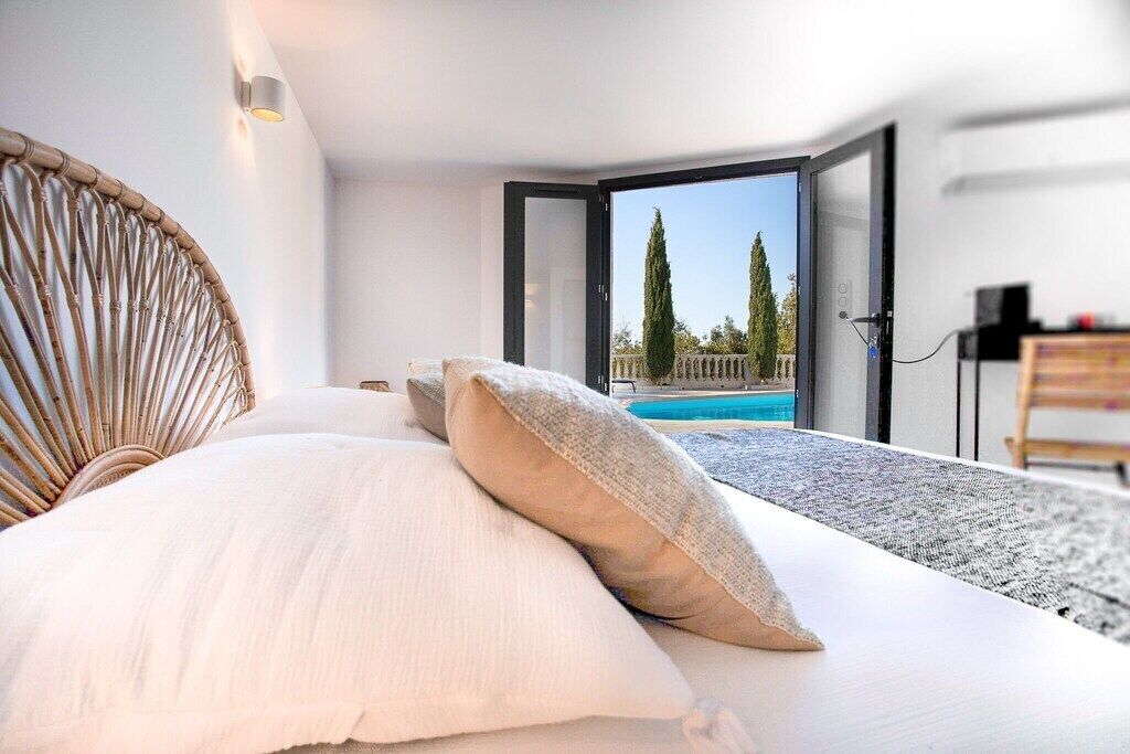 A modern bedroom with a large bed, a view of a swimming pool, and a door leading outside.