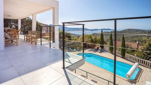 A modern outdoor pool area with a clear view of the sea and hills. - Superb 6 Bedroom Villa, Sea View, Swimming Pool & Pétanque, 5mn from the Beach (Lumio)