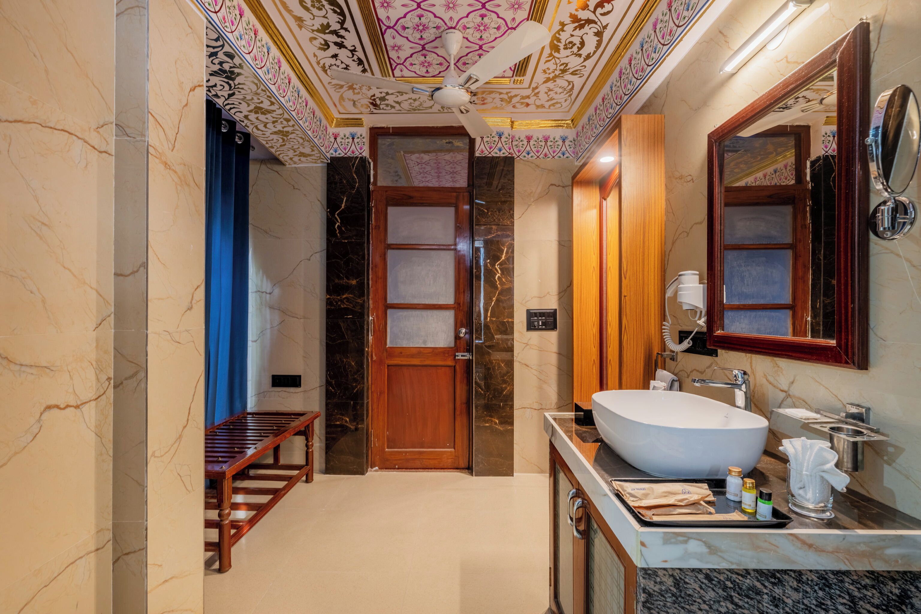 A bathroom with a large white sink, wooden door, and a mirror.