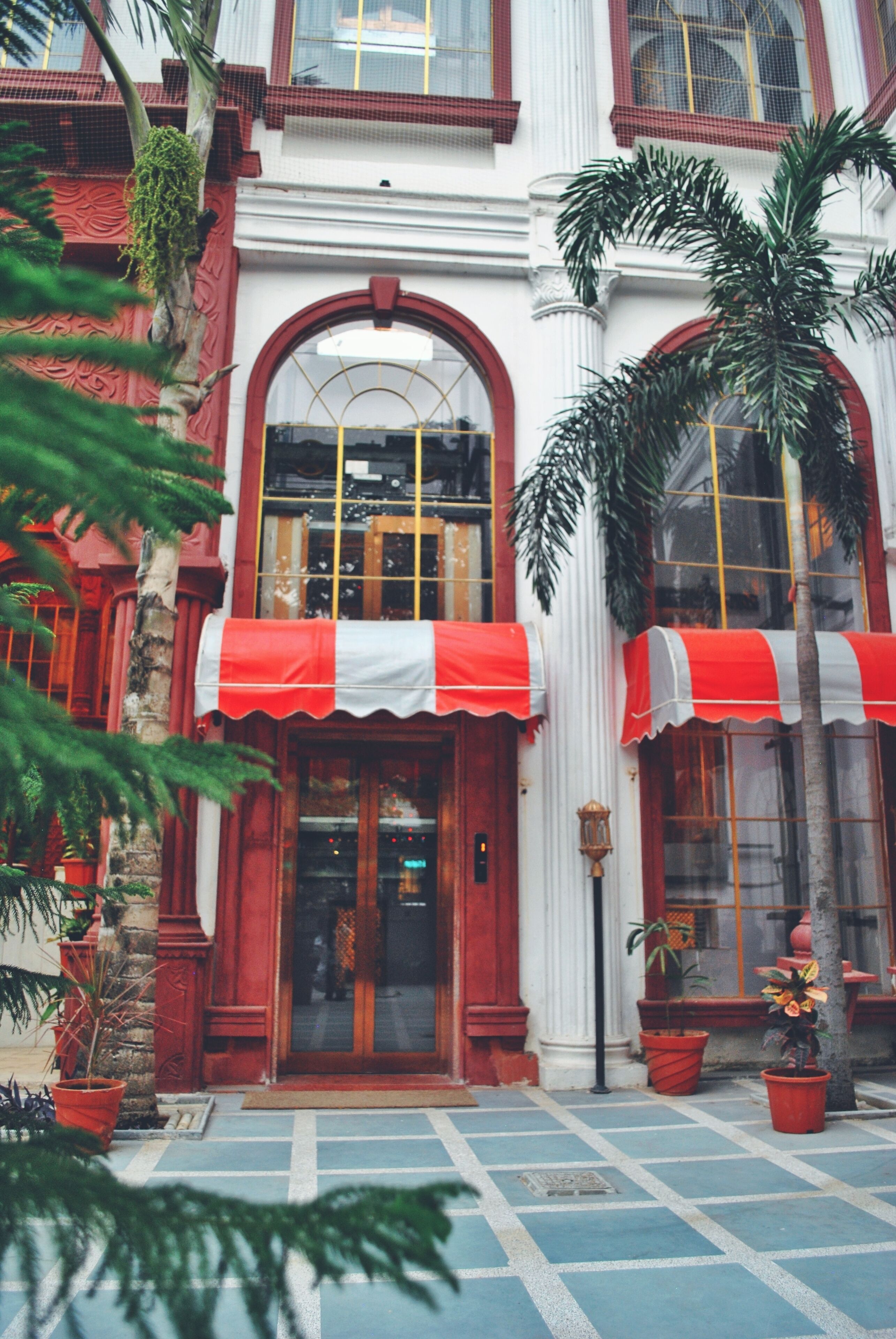 A building with a red and white awning, large windows, and a tiled entrance area.