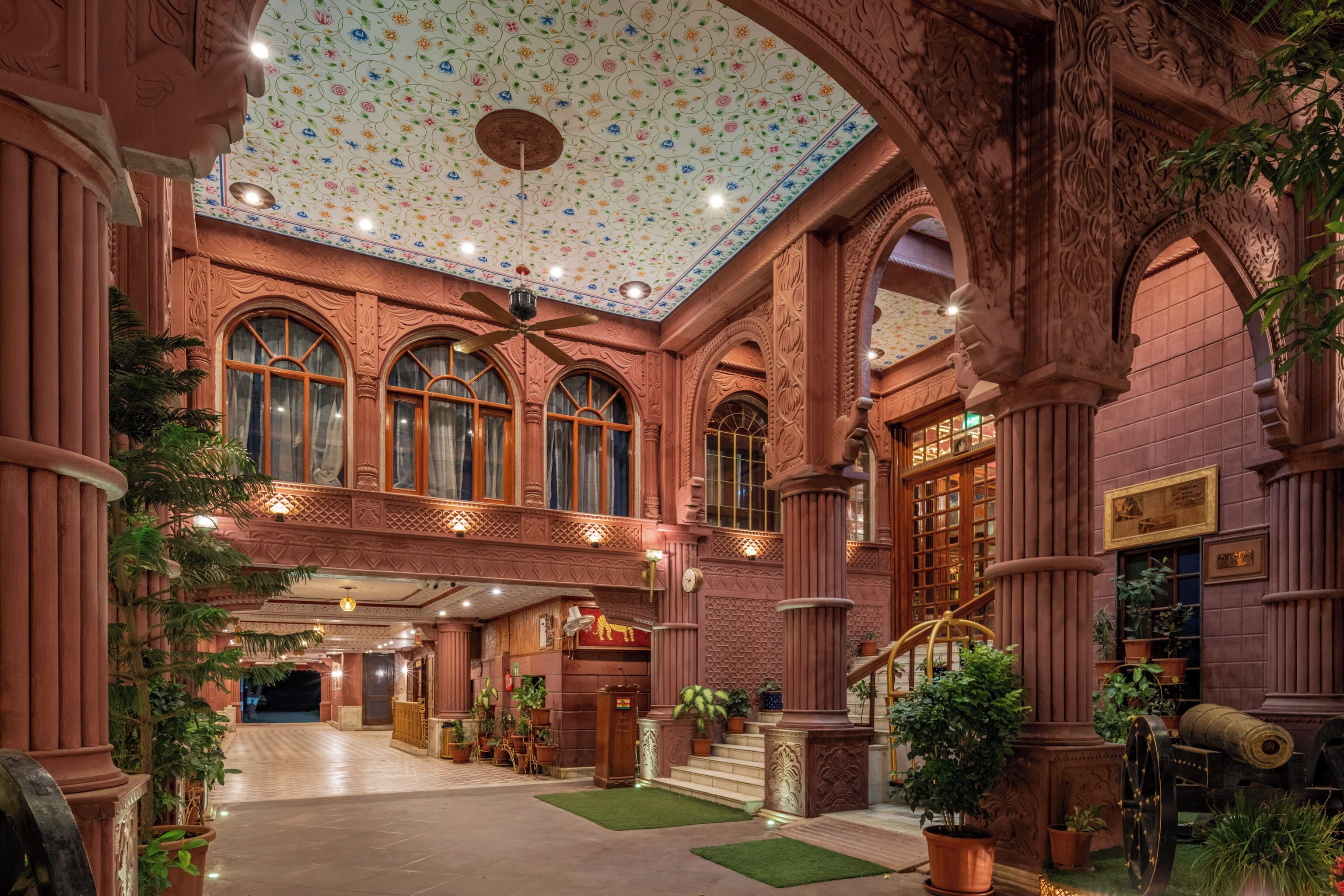 Un intérieur somptueux, avec un plafond haut, des colonnes richement décorées et un escalier central.