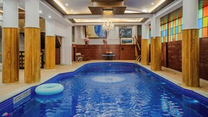 Ein Schwimmbecken mit Holzsäulen, einem Kronleuchter und einer farbenfrohen Wand.