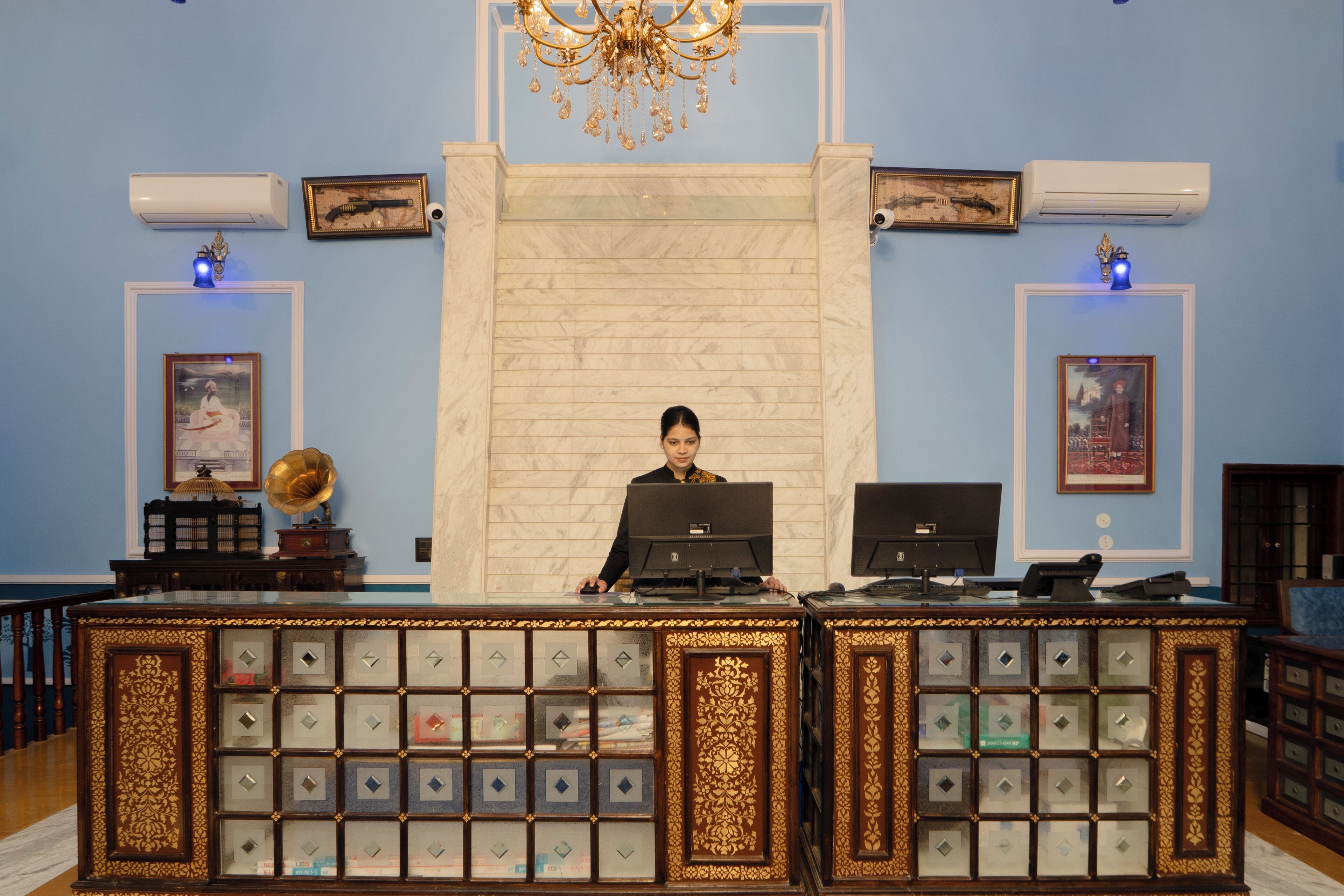 A reception desk with a marble wall and framed artwork.
