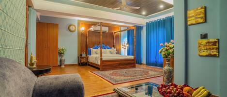 Un dormitorio con cama con dosel, una zona de estar con sofá y una mesa de comedor con fruta.