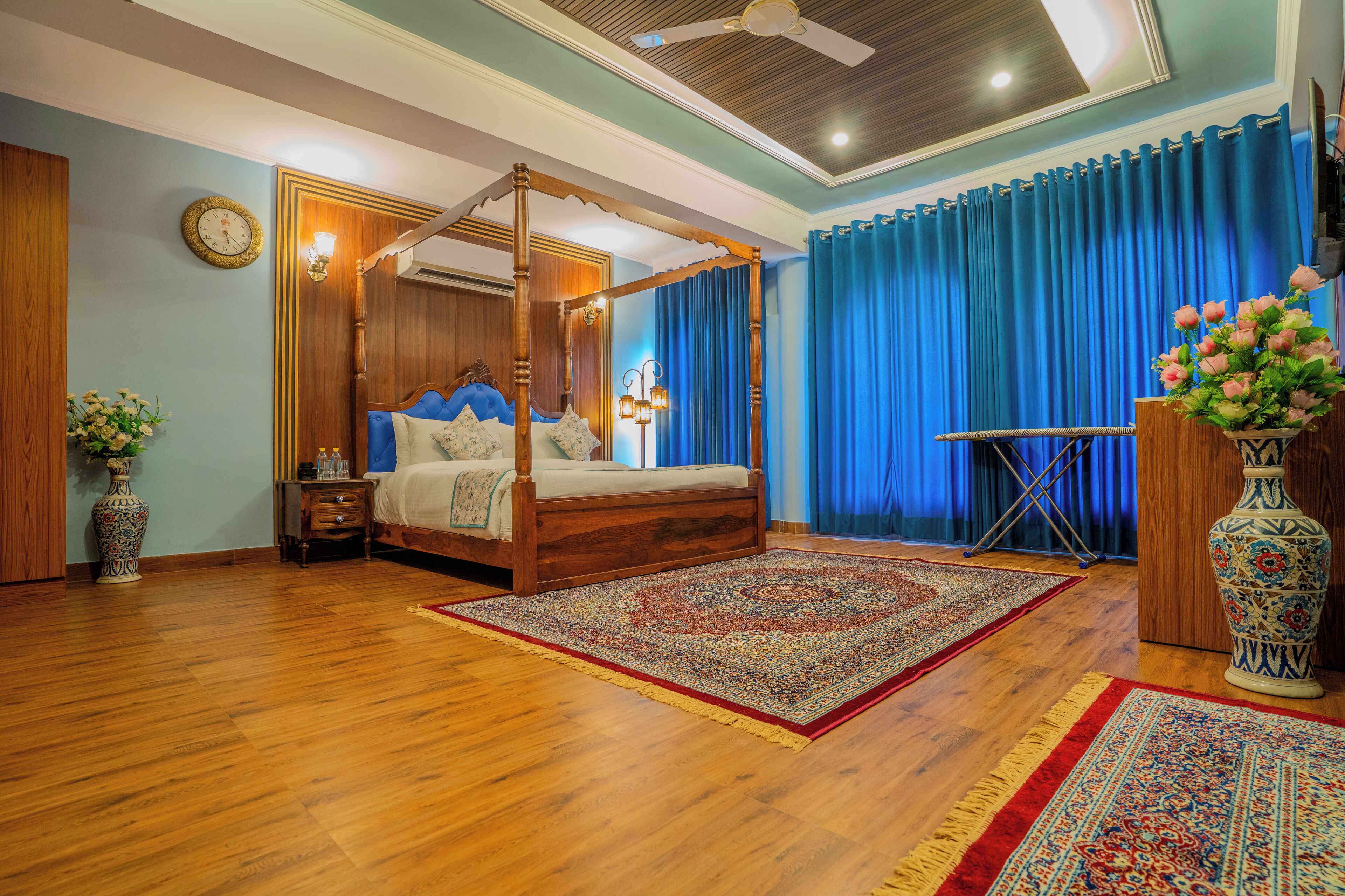 Une chambre spacieuse avec un lit à baldaquin, un grand tapis décoratif et un vase ornemental.