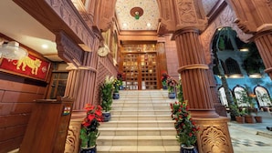Eine prächtige Treppe mit verzierten Säulen und floralen Verzierungen führt zu einer Holztür.