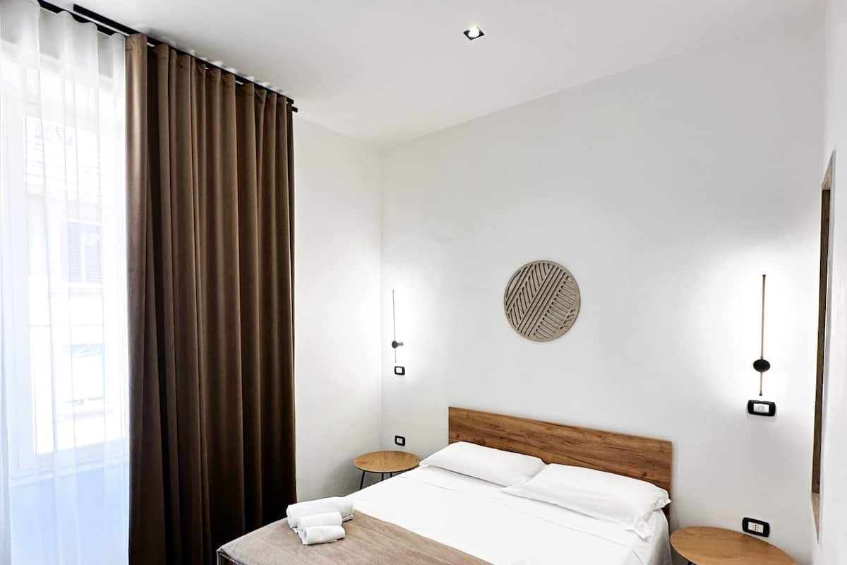 A modern hotel room with a wooden bed, a round wall decoration, and a small round table.