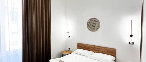 A modern hotel room with a wooden bed, a round wall decoration, and a small round table.