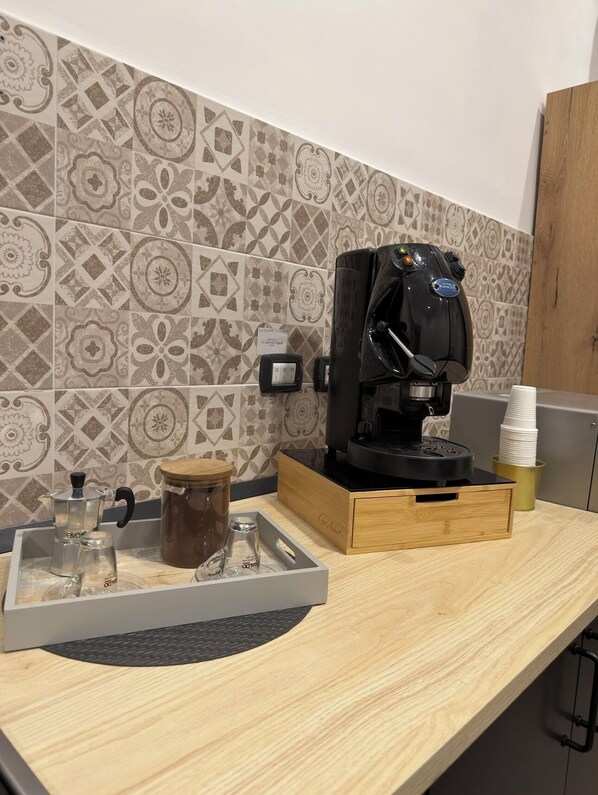 A kitchen counter with a coffee machine, a kettle, a glass carafe, and a coffee grinder. - Welcome to i Colori di Napoli (Naples)